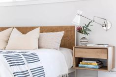 a bed with white sheets and pillows next to a wooden night stand