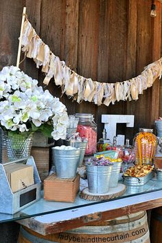 a table topped with buckets filled with lots of candy next to a wooden wall