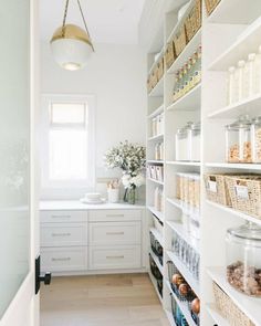 a white pantry with lots of shelves and baskets