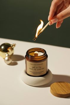 a person lighting a candle on top of a white table next to a gold teapot