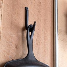 a cast iron skillet hanging on a wooden wall next to a hook and door