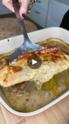 a person is spooning food out of a casserole dish with gravy