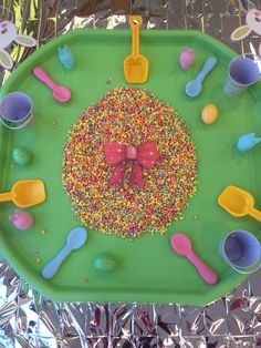 a green tray topped with lots of sprinkles and plastic spoons