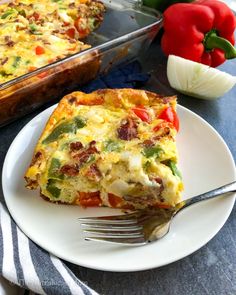 a slice of quiche on a white plate with a fork next to the casserole