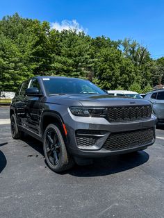 the front end of a gray jeep parked in a parking lot next to other cars