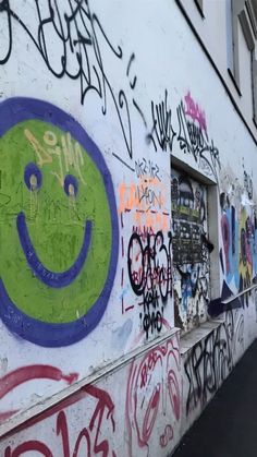 graffiti on the side of a building with a smiley face painted in purple and green