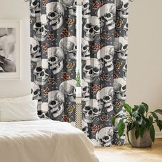 a white bed sitting next to a window covered in curtains and skulls on the wall