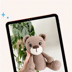 a hand holding a small teddy bear in front of a laptop screen with the image of a stuffed animal on it