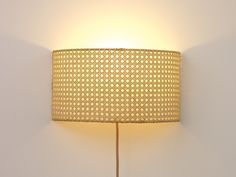 a lamp that is on the wall next to a white wall with a wooden stick underneath it