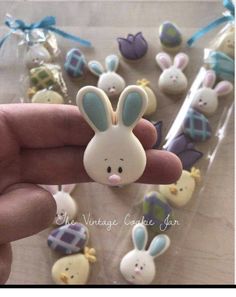 a hand is holding a small plastic bunny ornament in front of many other decorated cookies