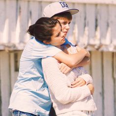 a boy and girl hugging each other outside