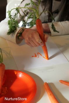 a person cutting carrots with a knife on a table