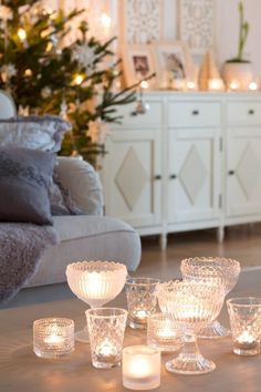 candles are sitting on the floor in front of a white couch and table with christmas decorations