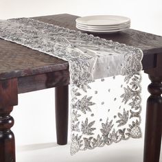 a table with a white plate on top of it and a silver lace over the edge