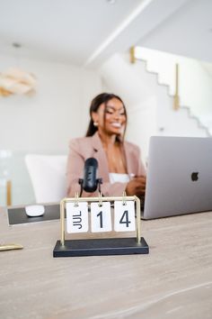 a woman sitting in front of a laptop computer on top of a wooden table next to a calendar