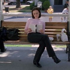 a woman sitting on a bench reading a book