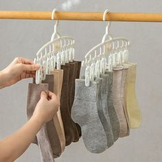 a person is holding several pairs of socks hanging from a rack with clothes on it