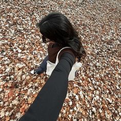 a woman with long black hair standing in the middle of an autumn leaf covered field