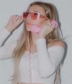 a woman wearing sunglasses and holding a pink phone to her ear