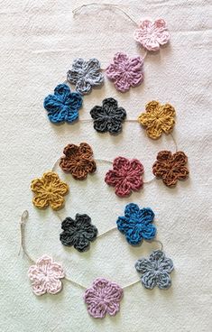 several crocheted flowers are arranged on a white surface, including one blue and one pink