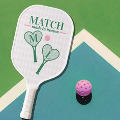 a tennis racket is next to a pink ball on the court, which says match made in heaven