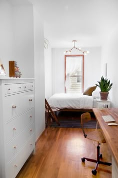 a bedroom with white walls and wooden floors