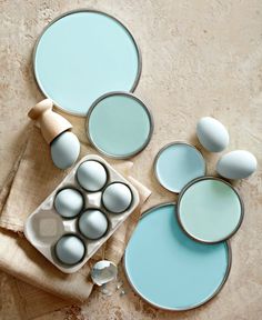 an assortment of eggs in tins on a table with blue and white paint colors