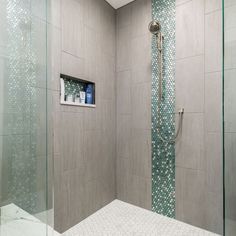 a walk in shower sitting next to a glass door and tiled wall with blue dots on it