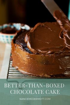 a person cutting into a chocolate cake on a cooling rack with a knife in it