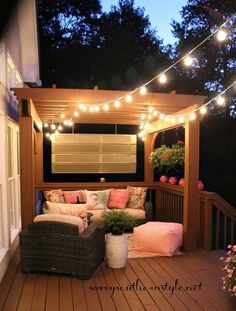 an outdoor patio with lights strung over it and furniture on the outside deck, along with potted plants