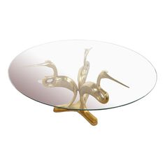 a glass table with two birds on it's legs and a gold metal base