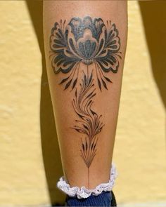 a woman's leg with a flower tattoo on the lower half of her leg