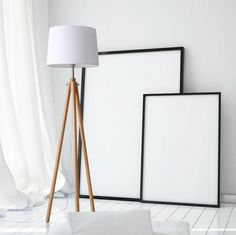 two frames on the floor next to a lamp and some white sheets in front of them