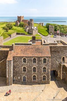 an aerial view of the castle and its surrounding grounds with people sitting on benches looking out over the water