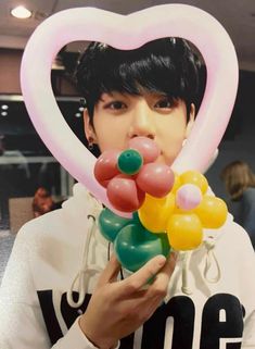 a person holding balloons in front of their face and heart shaped balloon on top of them