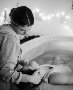 a woman is playing with her baby in the bathtub while it's being bathed