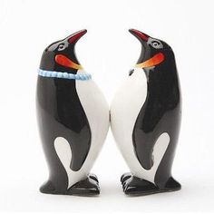 two black and white penguin figurines standing next to each other on a white background