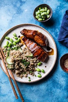 a plate with meat, rice and peas on it next to two bowls of beans