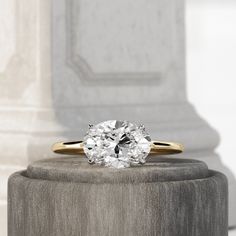 an oval cut diamond sits on top of a pedestal in front of a pillar and column