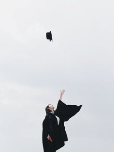 a graduate tossing her cap in the air while wearing a black gown and graduation hat