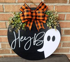 a black and orange door hanger with a ghost on it's side that says hey