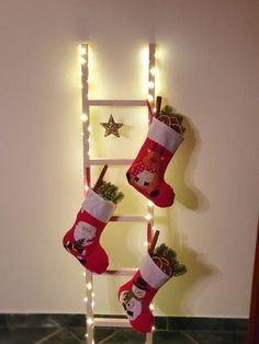 christmas stockings hanging from a ladder with lights around them and santa's stocking on it