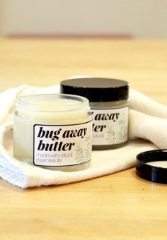 two jars of body butter sitting on top of a white towel next to a pair of scissors