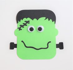 a paper cut out of the face of a green monster with googly eyes and black hair