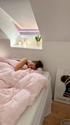 a woman laying in bed under a pink comforter