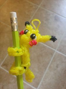 a yellow plastic toy holding a green pencil