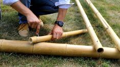 a man kneeling down next to a bamboo pole with two pieces cut out on it