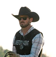 a man riding on the back of a brown horse wearing a cowboy hat and sunglasses