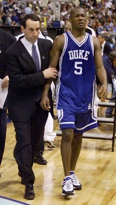 a man in a suit and tie walking on a court with another man behind him