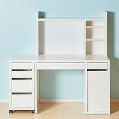 a white desk with two drawers and a bookcase on it in front of a blue wall